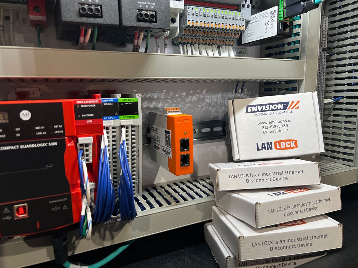 LAN Lock mounted on DIN rail next to a GuardLogix PLC, with boxed units ready to ship